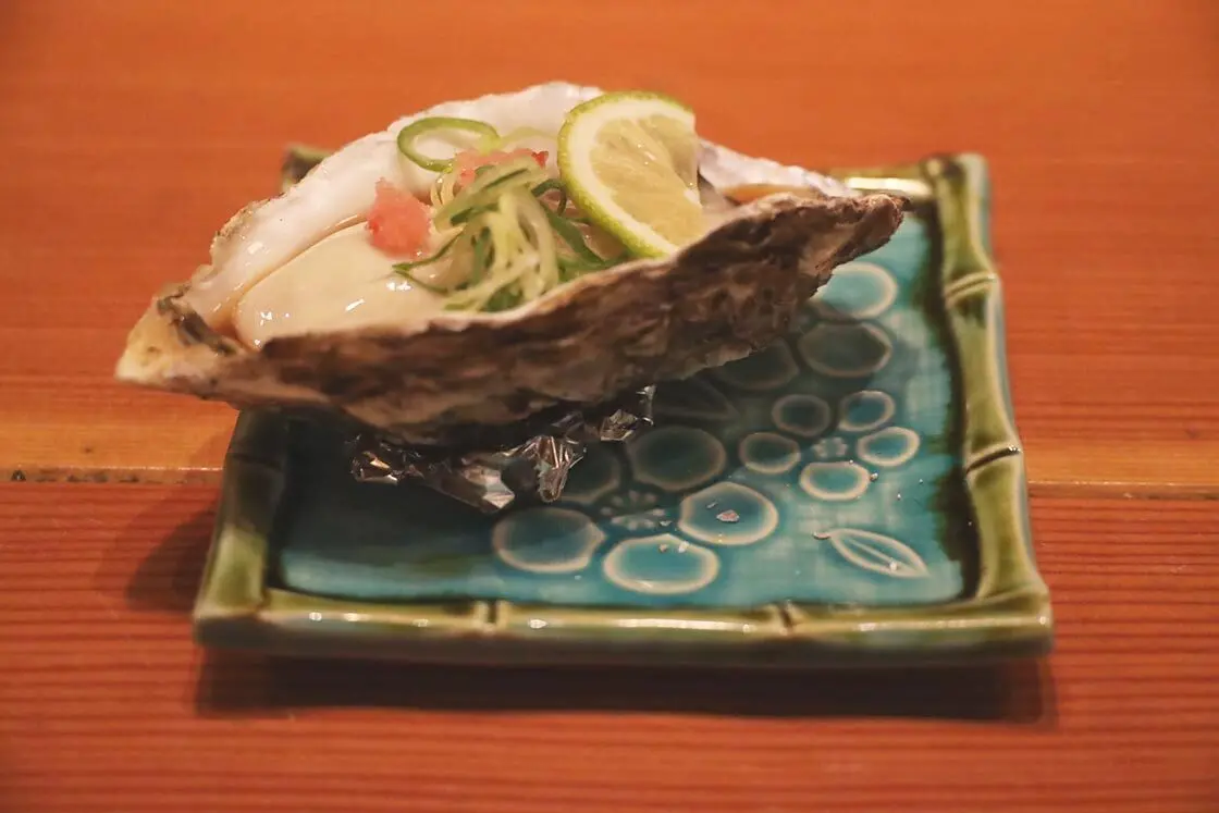 A raw oyster with green onion and ponzu